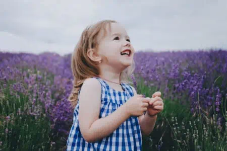 Adorable smiling toddler in blue dress in lavender field