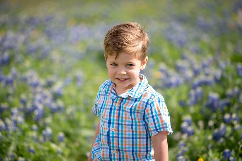 Cute toddler boy in checkered shirt in lavender field