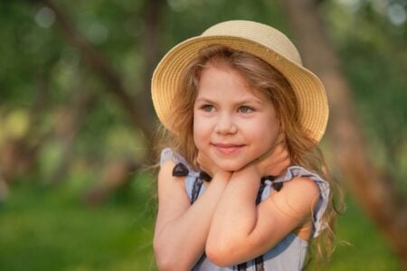 Cute little girl in a straw hat playing in the park