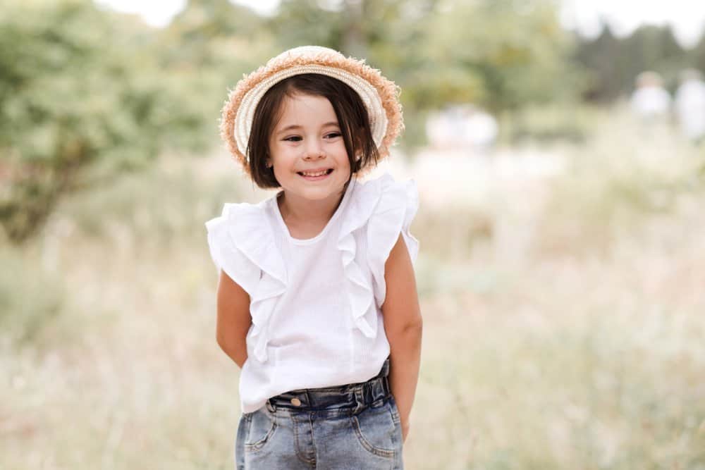 Happy little girl in a hat spending time outdoors