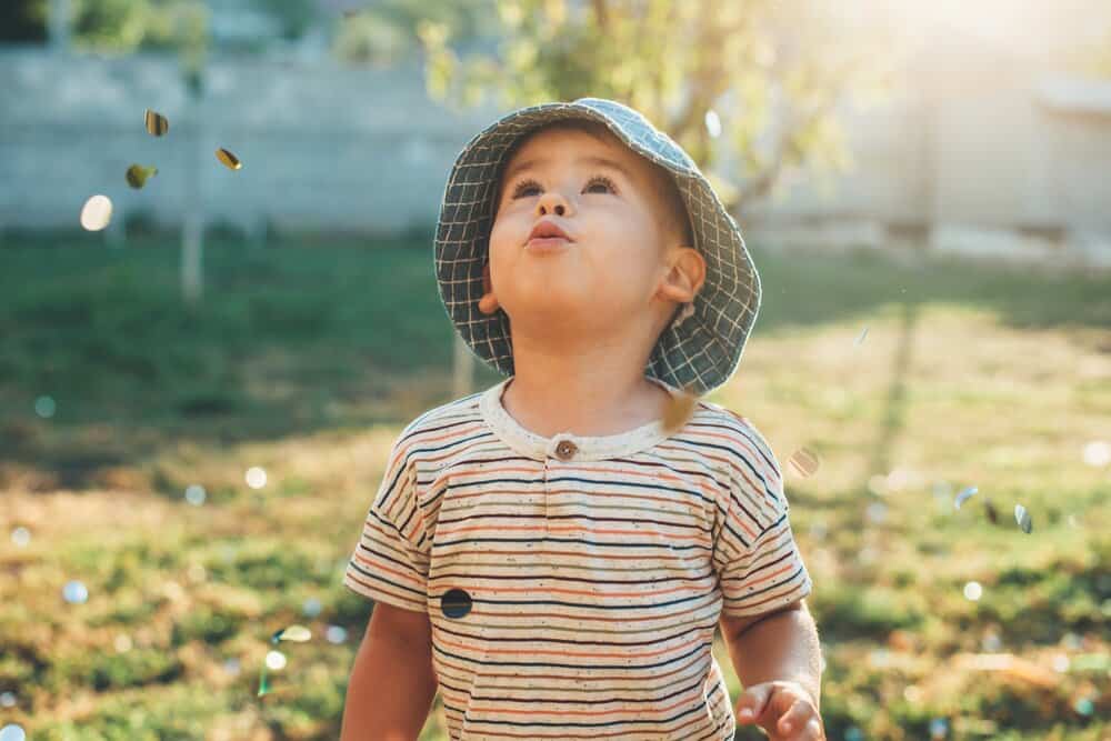 Cute little boy in a hat looking at the sky