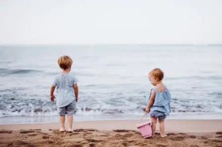 Two cute toddlers playing on the ocean beach.