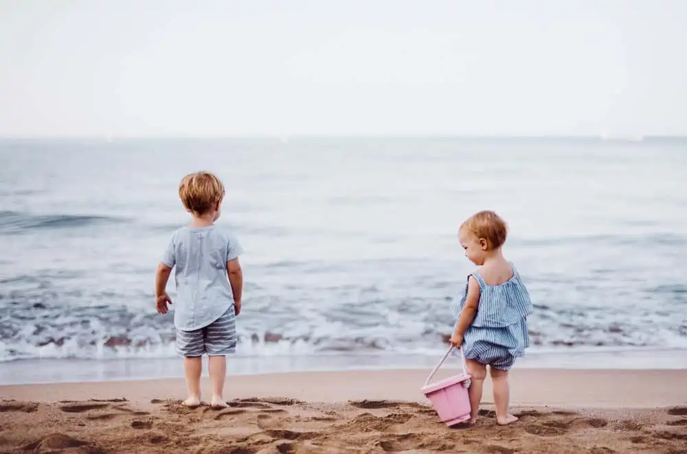 Two cute toddlers playing on the ocean beach.