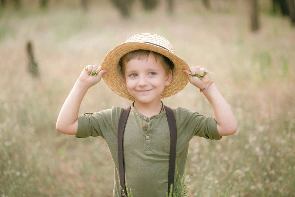 Cute little boy in a straw hat playing in the field