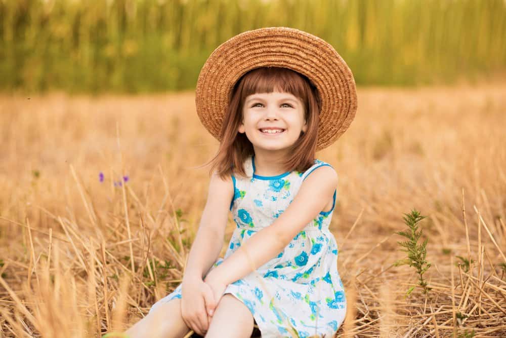 Happy little girl sitting in the wheat field