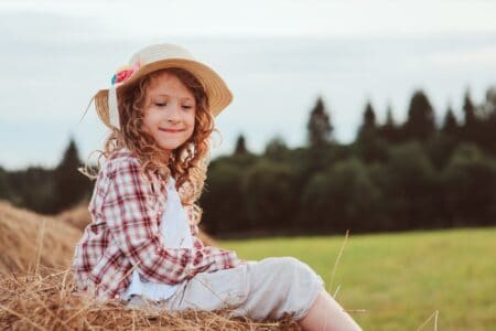 Happy smiling girl sitting on a haystack