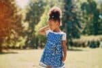 Beautiful little girl wearing dress walking in the park on sunny day