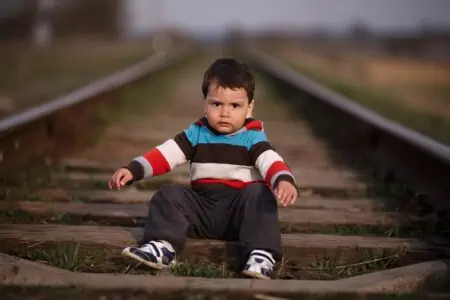 Little beautiful boy sitting on railroad