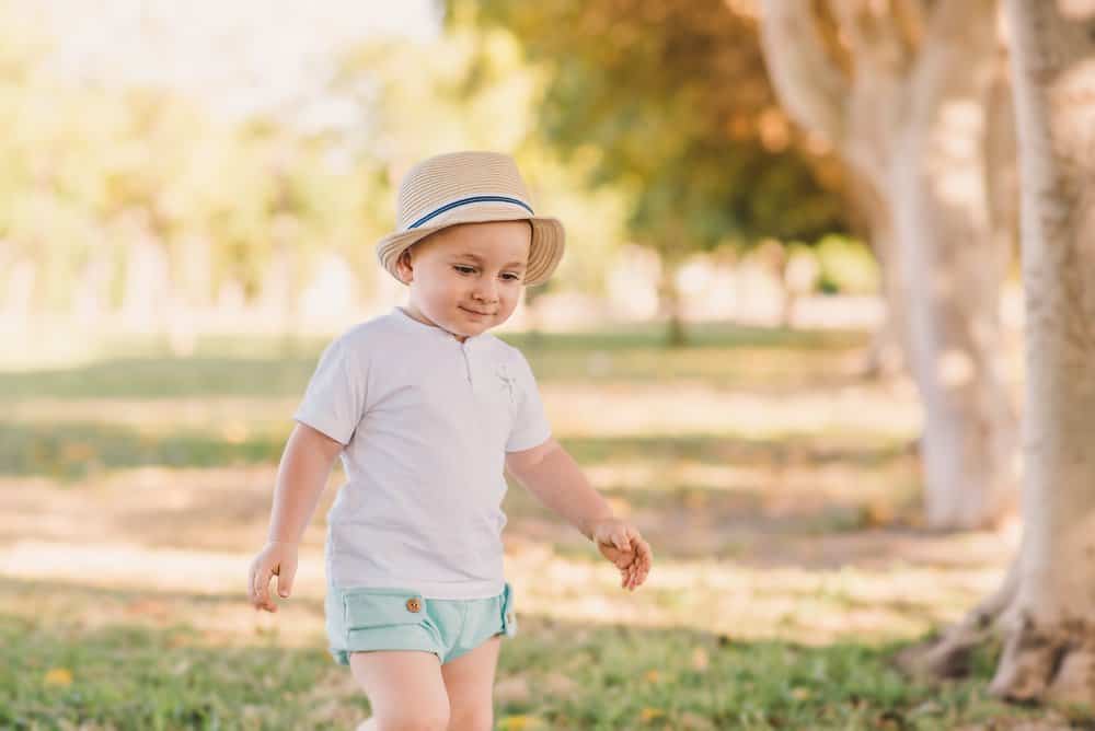 Little boy wearing hat walking in the forest