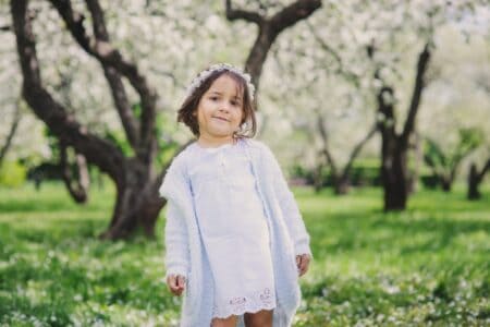 Adorable toddler girl wearing light blue dress and hairdress in the spring cherry park