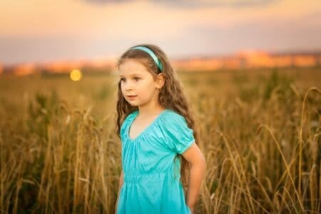 Happy girl in wheat field on warm and sunny summer sunset