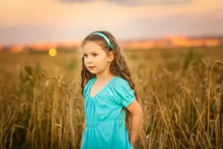 Happy girl in wheat field on warm and sunny summer sunset