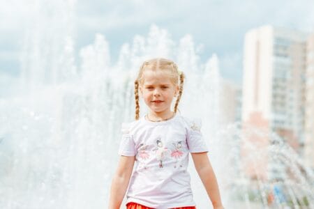 Cute little girl with pigtails near the fountain