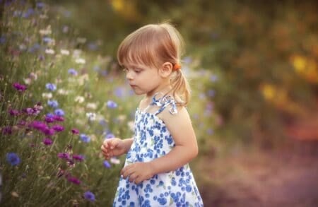 Pretty little girl wearing dress in summer flower field