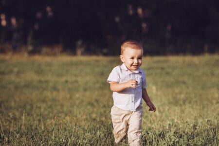 Little boy running in the field laughing happily