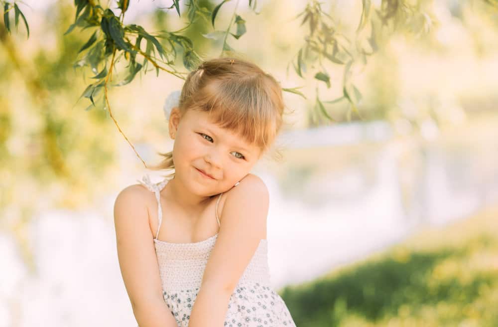 Adorable little girl on the river bank in the summer