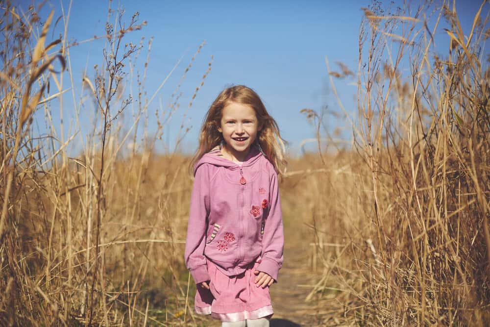 Happy little girl smiling in the autumn meadow