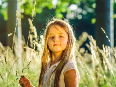 Cute little girl in the meadow during sunset
