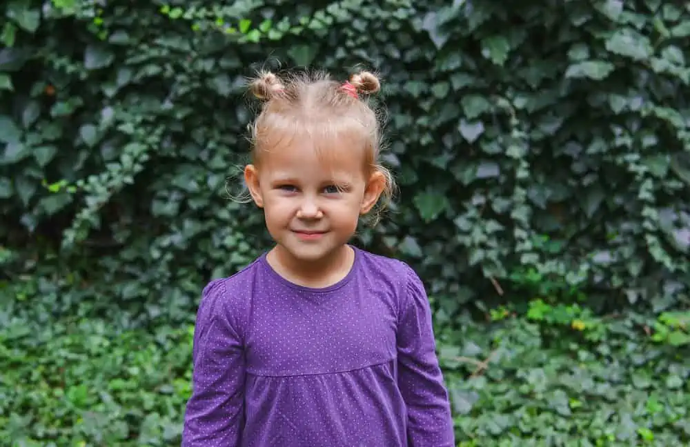Little young girl wearing purple shirt smiling looking into the camera