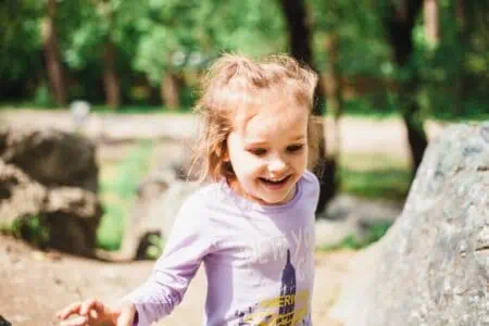 Adorable little girl in t-shirt climbing on rocks