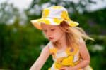 Adorable little girl wearing dress and hat with sunflower