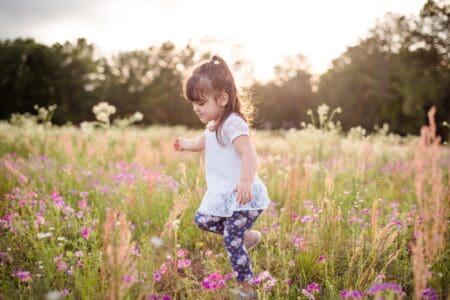 Adorable little girl walking in the flower field
