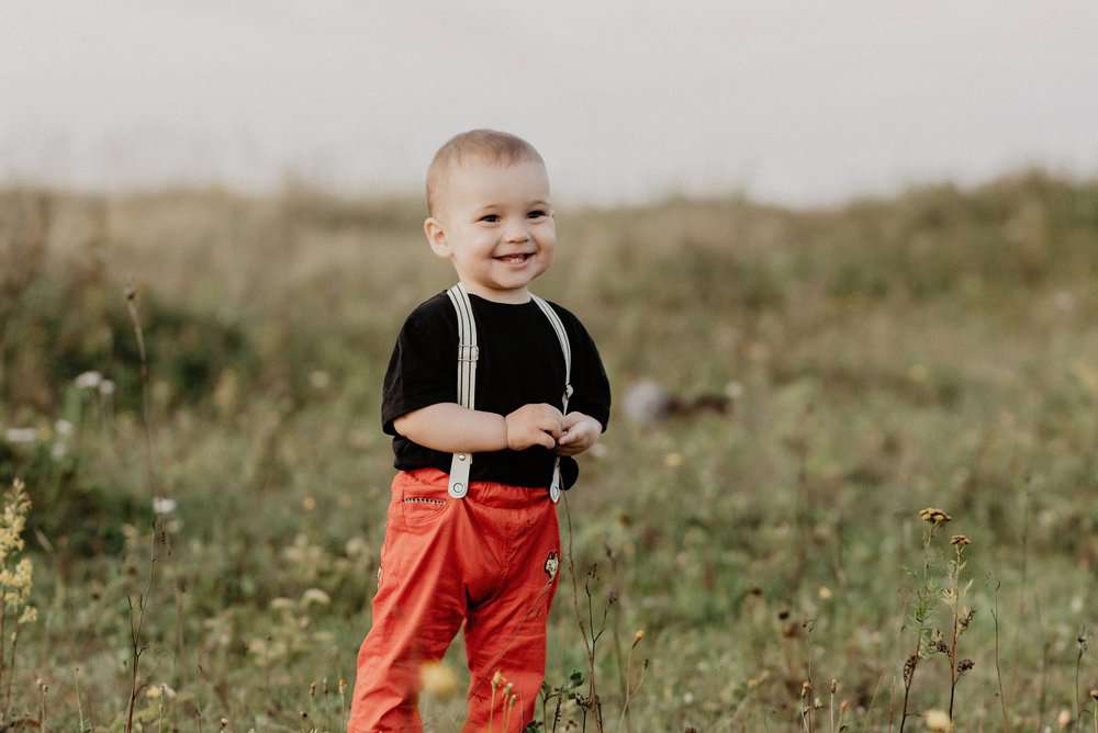 Happy cute little baby boy with spender smiling in autumn field