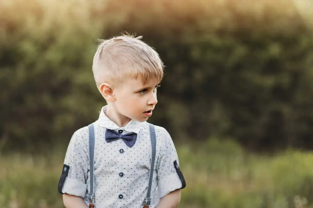 Blonde little boy with bow tie with nature background in summer