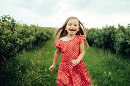 Beautiful young girl in red ploka dress having fun in the field