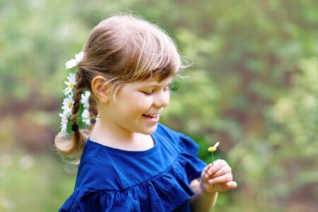 Happy little girl holding a daisy