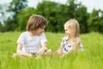 A boy and girl sitting in the field