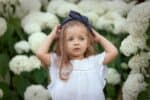 Adorable little girl standing in the flower garden