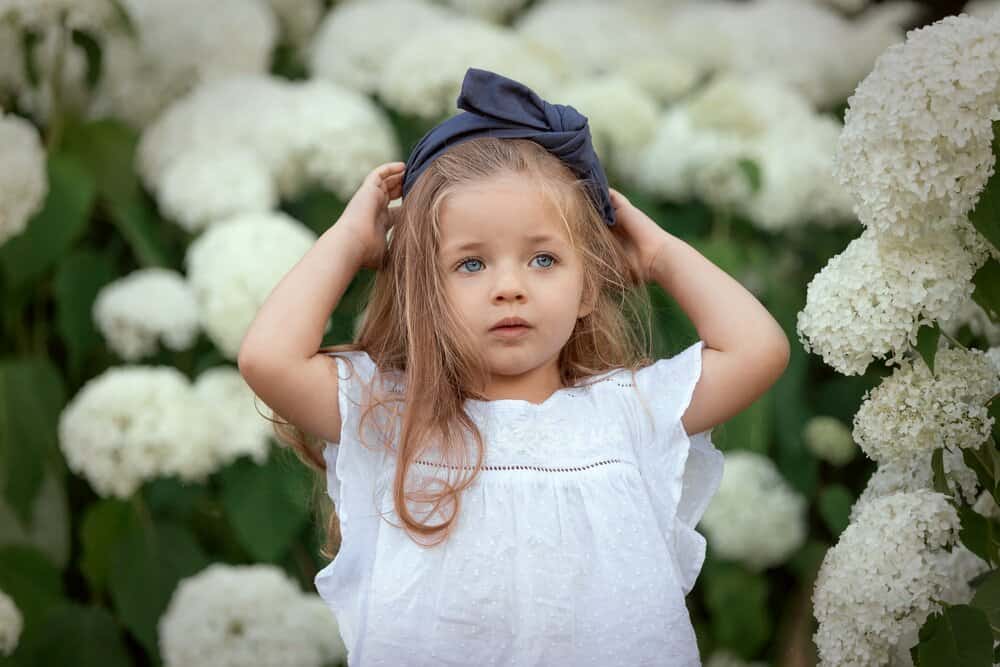 Adorable little girl standing in the flower garden