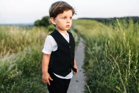 Cute little boy in a suit standing in the field