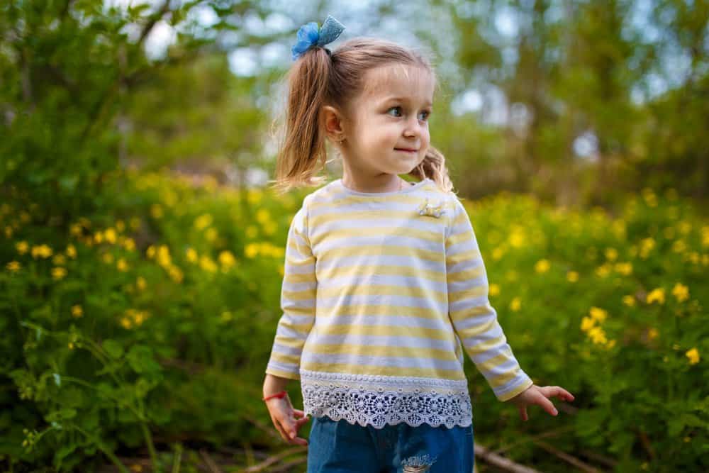 Cute little girl playing in flower field