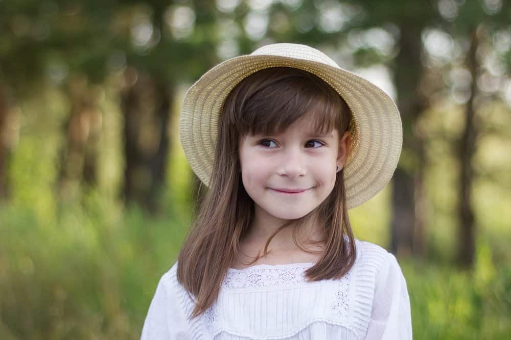 Happy little girl in a hat playing in the park
