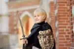 Little boy dressed as a medieval knight protects the gates of his castle