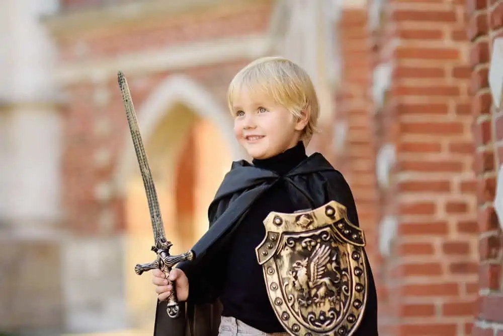 Little boy dressed as a medieval knight protects the gates of his castle
