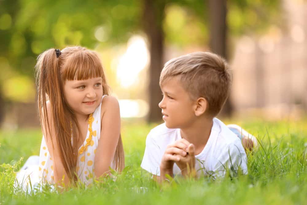 Cute little girl and boy lying on the grass