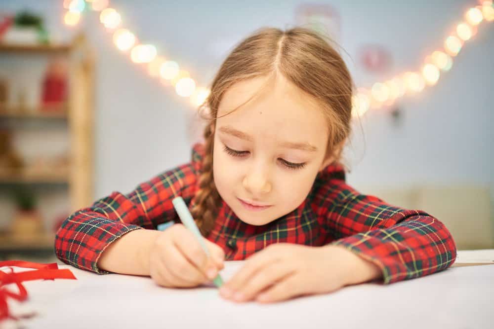 Little Scottish girl in tartan dress writing a letter