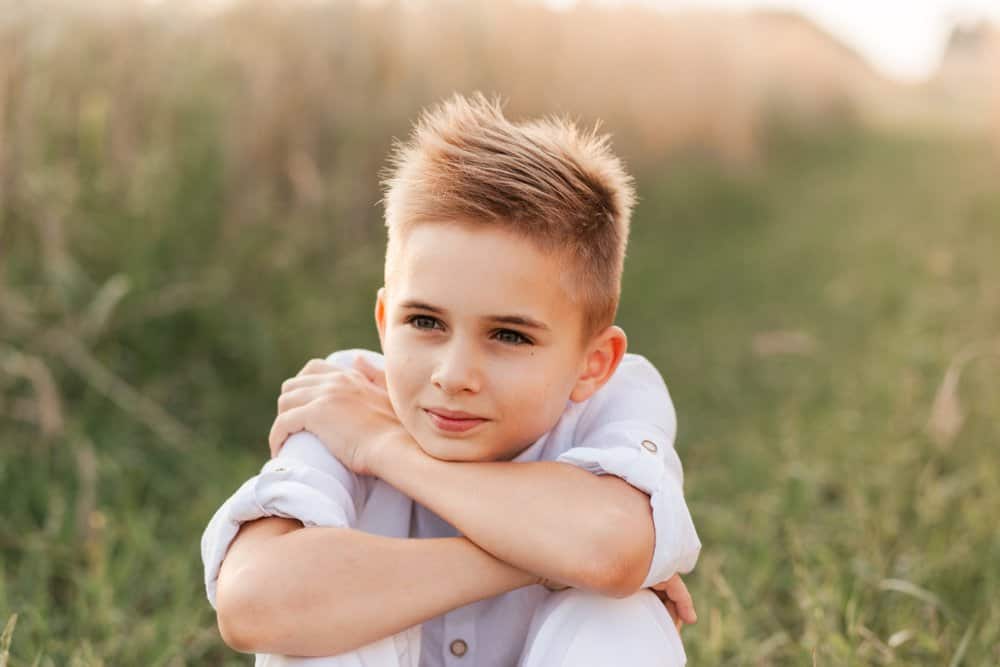 Little blond boy sitting in the field