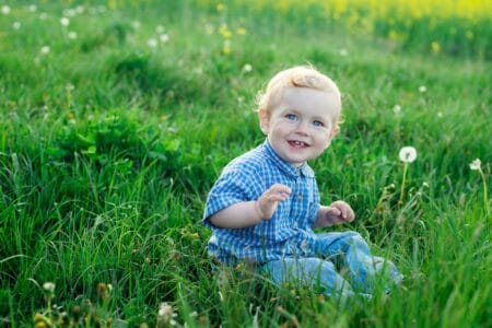 Cheerful baby boy sitting on the grass