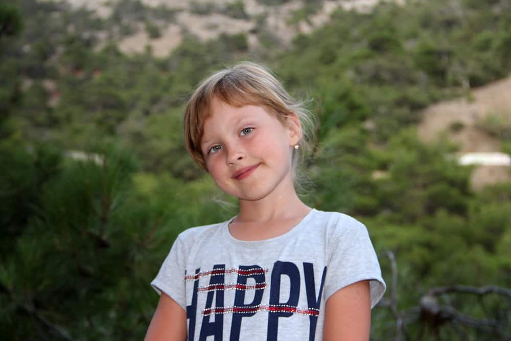 Smiling pretty young girl wearing shirt over nature background