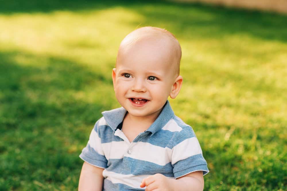 Adorable smiling baby boy playing in summer park