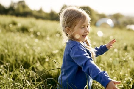 Little girl playing in the field on a sunny day