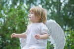Cute baby in an angel costume looking at the sky