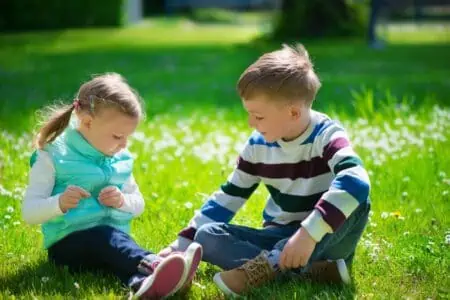 A girl and a boy sitting on the grass in the park