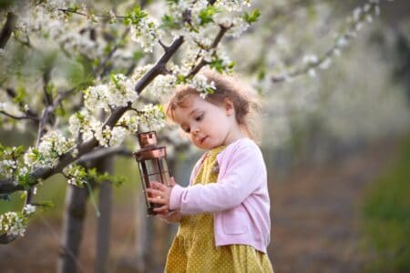 Cute little girl standing under a tree, holding a lantern