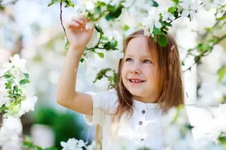 Smiling little girl looking at the flowers in the park
