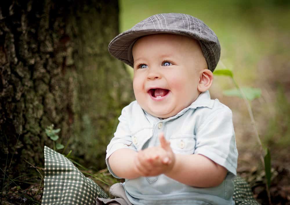 Happy little boy in a tartan hat sitting on the grass